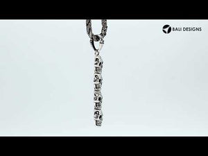 Sterling silver vertical skull pendant with carved detailing and polished finish.