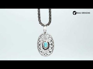 A handcrafted sterling silver pendant featuring a radiant Blue Topaz Quartz gemstone centered in an elegant Balinese filigree oval frame.