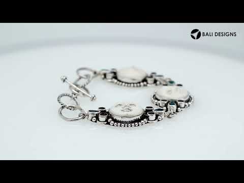 Sterling silver bracelet featuring carved bone faces with Garnet Quartz and Blue Topaz Quartz accents and an artisan toggle lock.