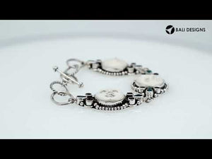 Sterling silver bracelet featuring carved bone faces with Garnet Quartz and Blue Topaz Quartz accents and an artisan toggle lock.