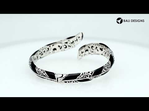 Wholesale sterling silver feather-inspired bangle featuring bold Black Shell inlays, ornate Balinese scroll engraving, and a secure hinge lock for premium artisan-inspired jewelry collections.