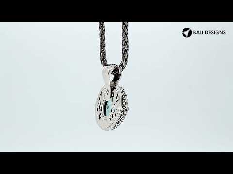 Sterling silver oval pendant featuring a vibrant Blue Topaz Quartz center decorated with intricate Balinese scroll carvings and a smooth, polished artistic frame.