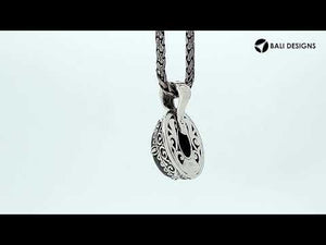 Sterling silver oval pendant featuring a vivid Ruby Quartz centerpiece highlighted by detailed Balinese scroll carvings and a smoothly polished artistic frame design.