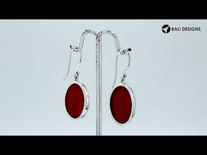 Wholesale sterling silver earrings featuring oval red coral drops with a polished wave-motif overlay, offering reliable craftsmanship and elegant presentation suitable for bulk jewelry orders.