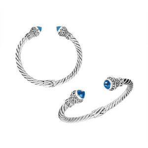 Wholesale sterling silver twisted cable cuff bracelet with faceted blue topaz quartz end caps, hinge lock, and ornate Balinese engravings for premium jewelry collections.