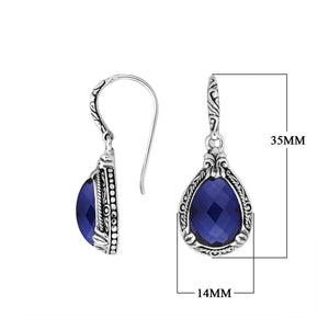 Wholesale sterling silver earrings featuring a deep-blue faceted Sapphire teardrop framed with ornate carved borders and secured with an earwire lock, offering regal brilliance and structured artisan appeal for premium wholesale presentations.