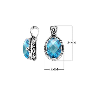 Sterling silver oval pendant featuring a vibrant Blue Topaz Quartz center decorated with intricate Balinese scroll carvings and a smooth, polished artistic frame.