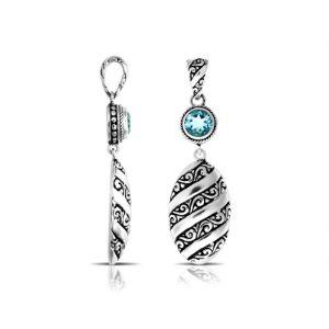 A wholesale Silver Overlay Over Copper pendant featuring a sparkling blue topaz quartz stone, detailed Balinese spiral patterns, oxidized textures, and polished highlights ideal for bulk jewelry purchasing.