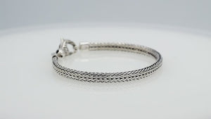 A beautifully crafted sterling silver woven bracelet with a secure lobster clasp, featuring intricate chain detailing and a mirror-polished high-gloss finish for elegant collections.