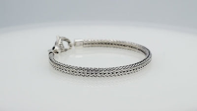A beautifully crafted sterling silver woven bracelet with a secure lobster clasp, featuring intricate chain detailing and a mirror-polished high-gloss finish for elegant collections.