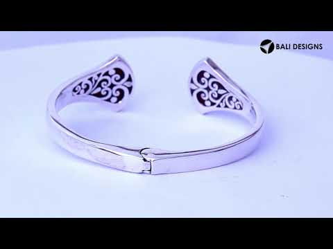 Wholesale sterling silver cuff featuring sculpted ends with bold Red Coral inlays, polished finishing, and a secure hinge lock for catalog-ready bulk presentation.