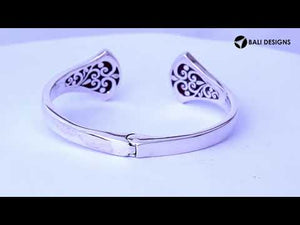 Wholesale sterling silver cuff featuring sculpted ends with bold Red Coral inlays, polished finishing, and a secure hinge lock for catalog-ready bulk presentation.