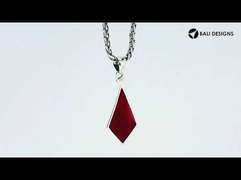 A handcrafted sterling silver pendant featuring a vibrant Red Coral encased in a geometric triangular frame, combining modern design and Balinese craftsmanship.