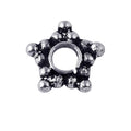 Star-shaped granulated spacer bead in silver overlay over copper with oxidized detailing and open circular center.